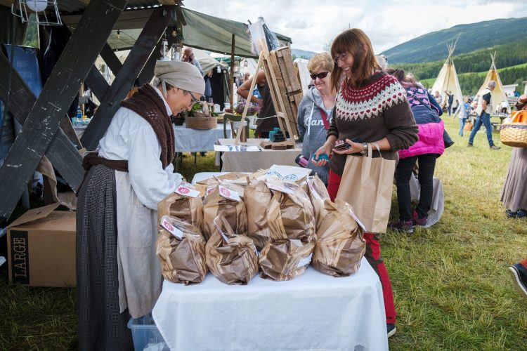 Spectators visiting Jamtjordmartnan and buying local products from one of the venders, dressed in old costumes.